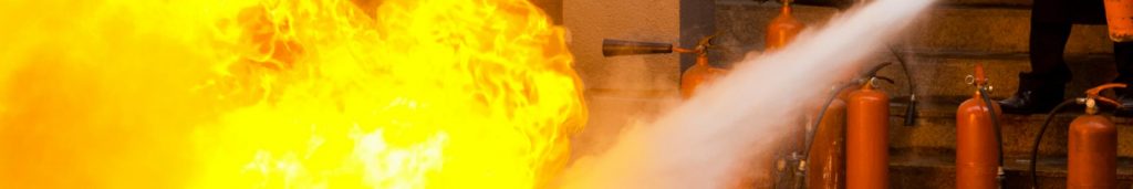 Instructor demonstrates proper fire extinguisher techniques while battling a planned fire during a spanish safety course.