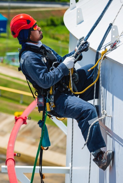 Male worker down height tank roof rope access safety inspection of thickness storage tank gas propane.