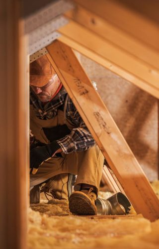 Air Ventilation Installer Working in Attic. Air Quality Heating and Cooling System Building by Professional Technician.