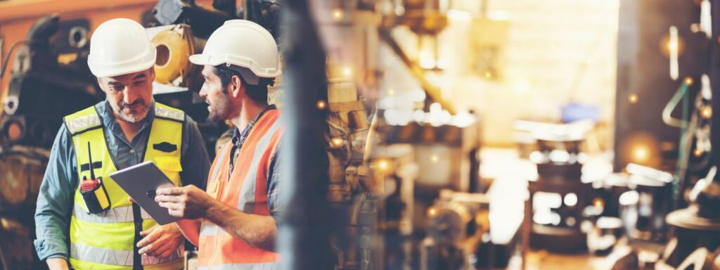 Caucasian factory engineer talking and shaking hands on business cooperation agreement. Successful hand shaking after good deal, workers handshaking each other at heavy industrial production line.