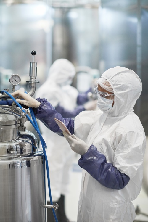 Vertical portrait of worker wearing protective suit while operating equipment and carrying out a risk assessment