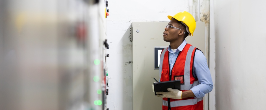 Technician engineering man working on tablet computer checking transformer in factory for EHS compliance